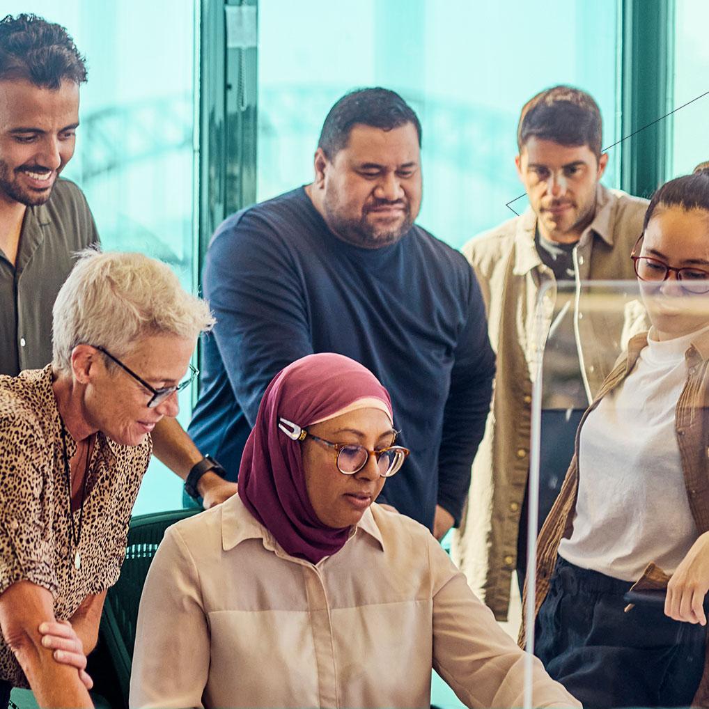 Office staff gather around a desk